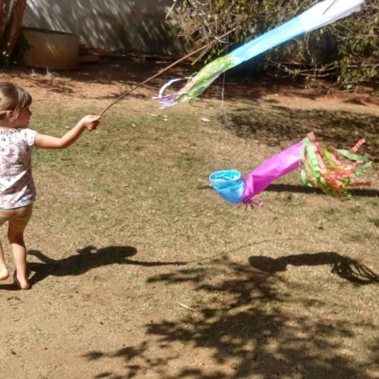 Criança correndo com uma pipa colorida no terreno da escola