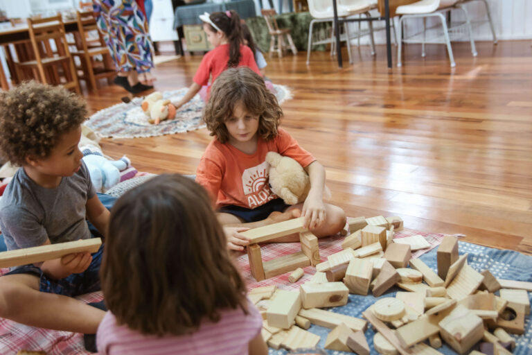 Crianças pequenas brincando com blocos de madeira no chão da sala
